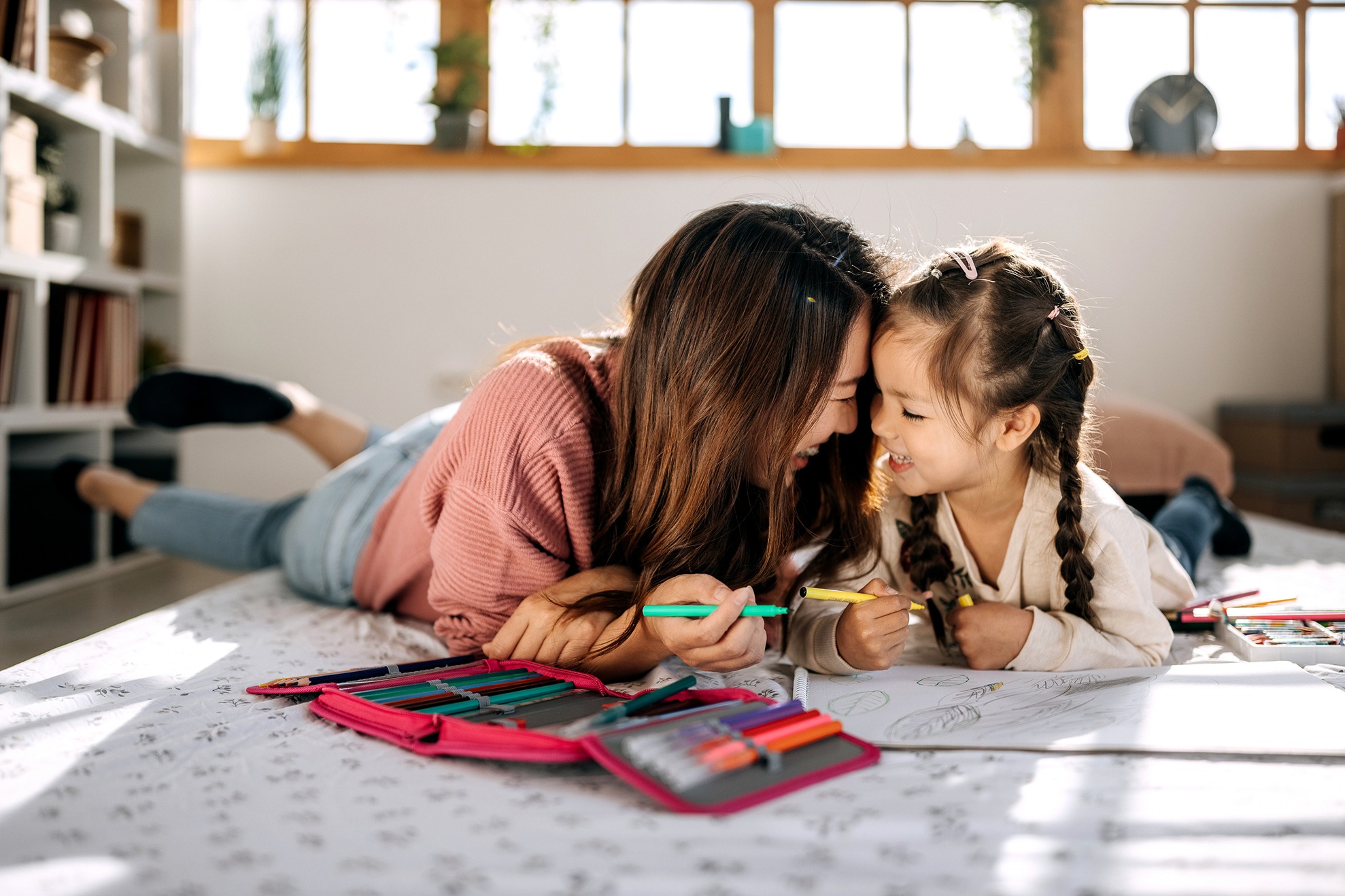 A young mother is coloring with her happy child.
